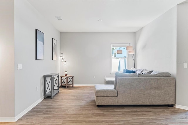 living room featuring light wood-style floors, visible vents, and baseboards