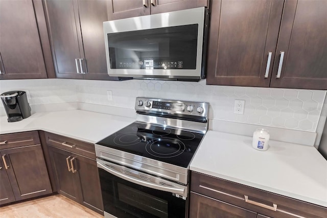 kitchen with dark brown cabinets, backsplash, stainless steel appliances, and light countertops