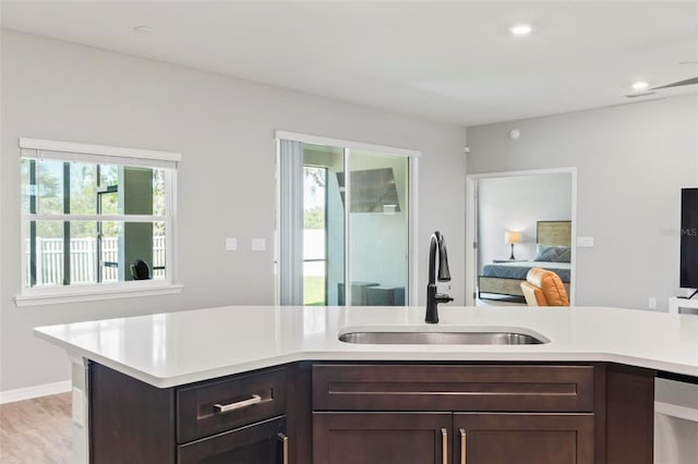 kitchen featuring light wood-type flooring, a sink, recessed lighting, dark brown cabinetry, and light countertops