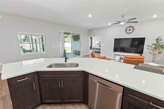 kitchen featuring a ceiling fan, a sink, light countertops, stainless steel dishwasher, and open floor plan