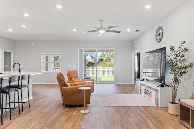 living area with recessed lighting, baseboards, light wood-type flooring, and a ceiling fan