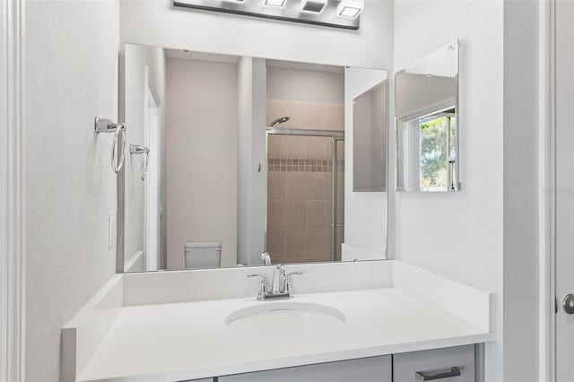 bathroom featuring tiled shower, toilet, and vanity