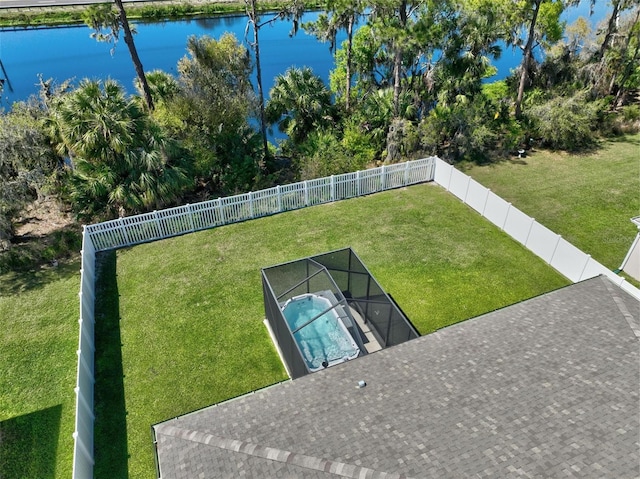 view of yard featuring glass enclosure, a fenced backyard, and a water view