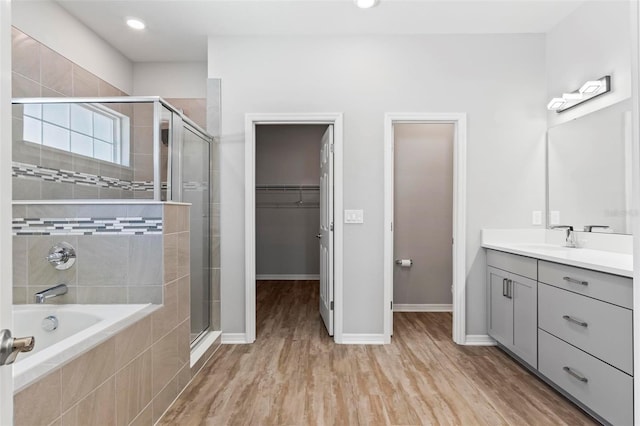 149 St Thomas Dr, Mulberry, FL 33860 - bathroom with a stall shower, a bath, vanity, wood finished floors, and a walk in closet