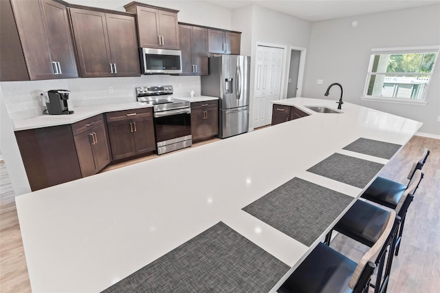 149 St Thomas Dr, Mulberry, FL 33860 - kitchen with appliances with stainless steel finishes, a kitchen breakfast bar, dark brown cabinetry, light countertops, and tasteful backsplash