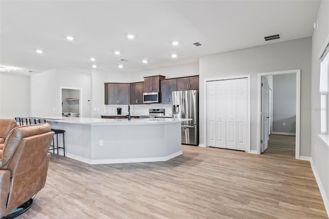 149 St Thomas Dr, Mulberry, FL 33860 - kitchen featuring stainless steel appliances, open floor plan, dark brown cabinetry, light countertops, and light wood-style floors