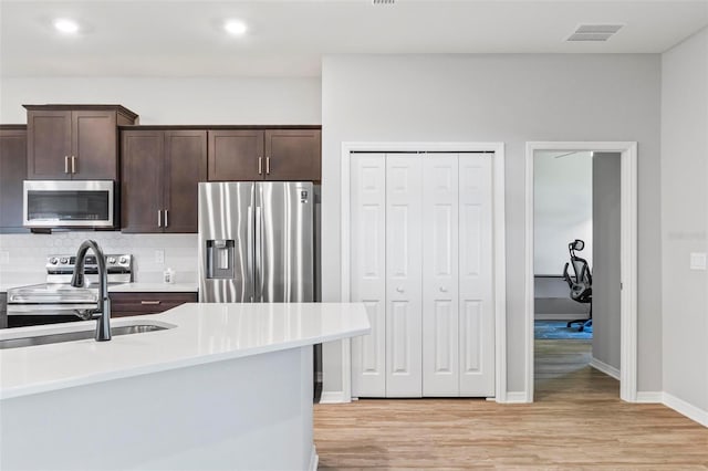 149 St Thomas Dr, Mulberry, FL 33860 - kitchen featuring stainless steel appliances, dark brown cabinetry, light wood-style flooring, light countertops, and recessed lighting