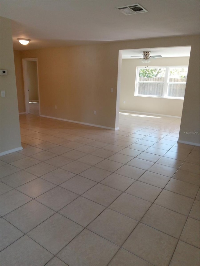 empty room featuring light tile patterned flooring, visible vents, and baseboards