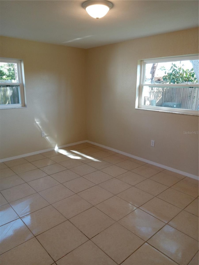 spare room featuring light tile patterned floors and baseboards