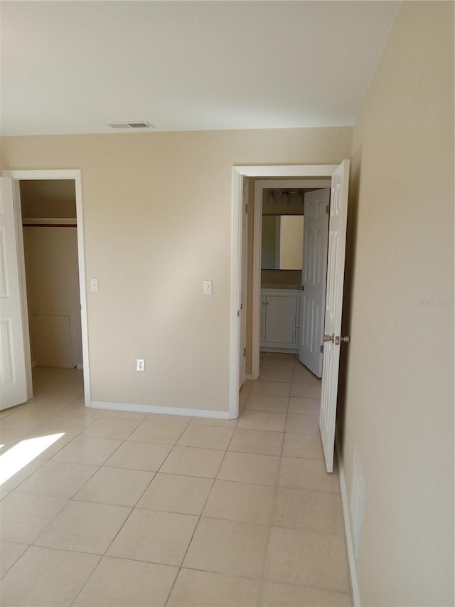 unfurnished bedroom with light tile patterned floors, visible vents, and baseboards