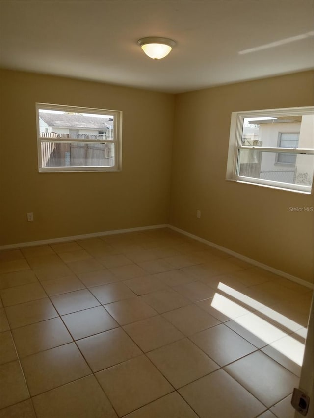 tiled empty room with baseboards and plenty of natural light