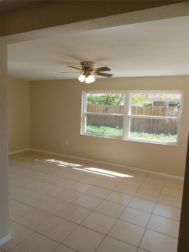 empty room with light tile patterned flooring, ceiling fan, and baseboards