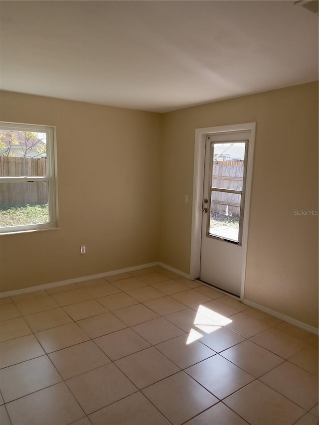 empty room with light tile patterned flooring and baseboards