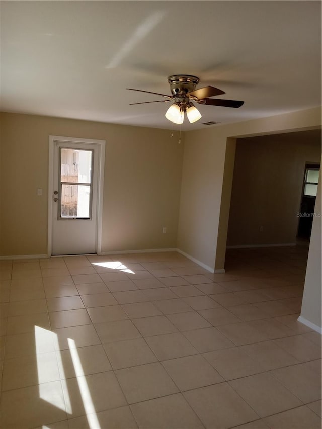 empty room featuring light tile patterned floors, visible vents, baseboards, and ceiling fan