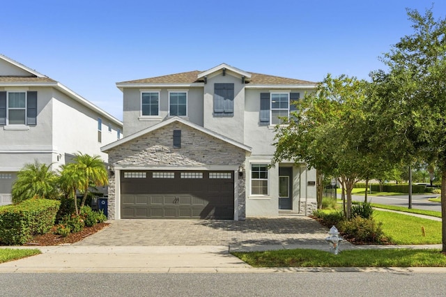 traditional-style home featuring stone siding, stucco siding, driveway, and a garage