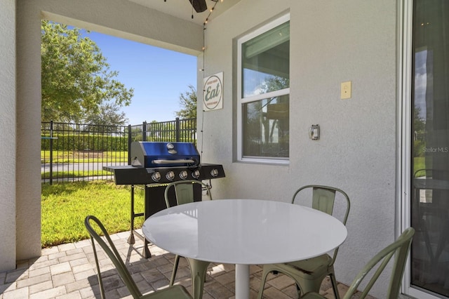 view of patio with outdoor dining area, fence, and a grill