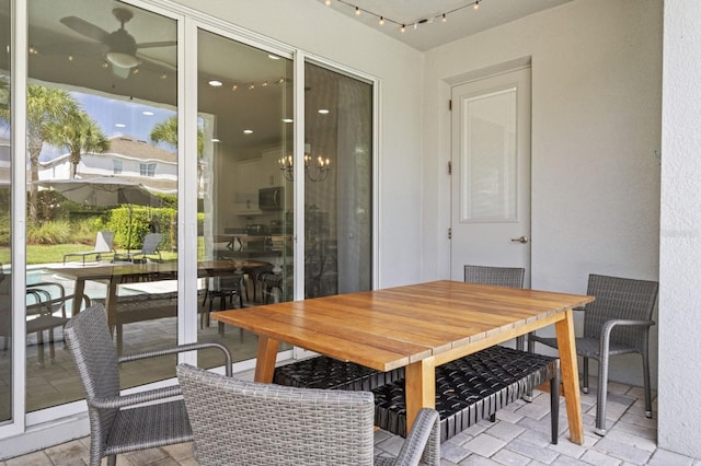 exterior space featuring track lighting and ceiling fan with notable chandelier