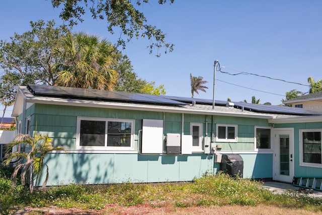 back of property featuring roof mounted solar panels