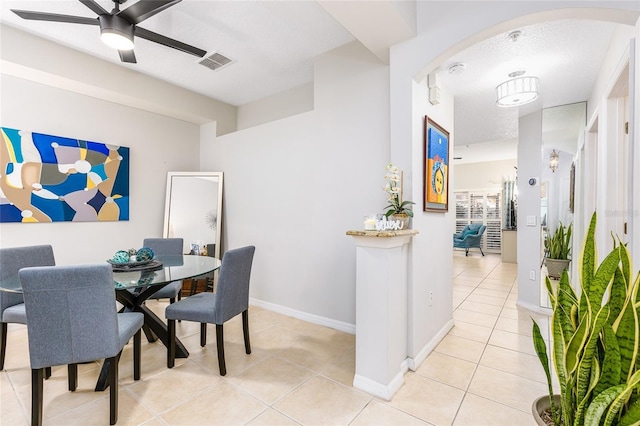 dining space featuring visible vents, arched walkways, light tile patterned flooring, baseboards, and ceiling fan