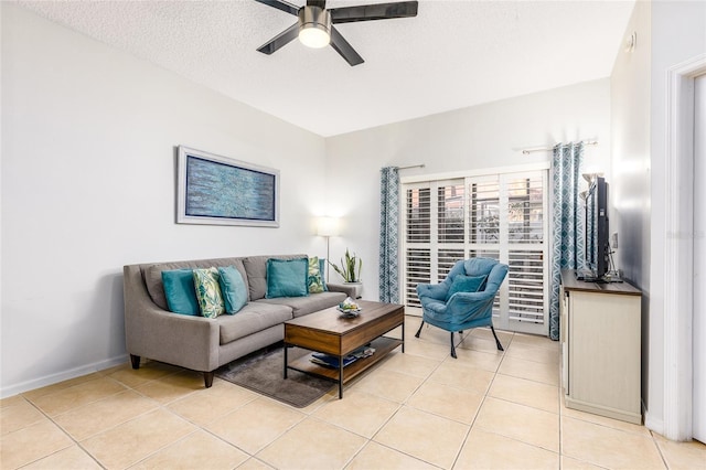 living area featuring light tile patterned flooring, baseboards, a textured ceiling, and a ceiling fan