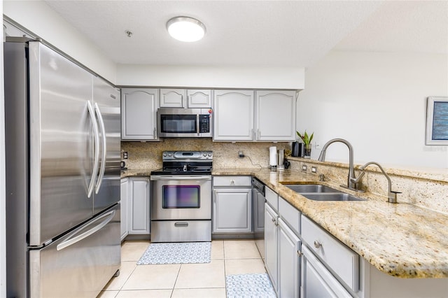 kitchen with a sink, light tile patterned floors, gray cabinets, and stainless steel appliances