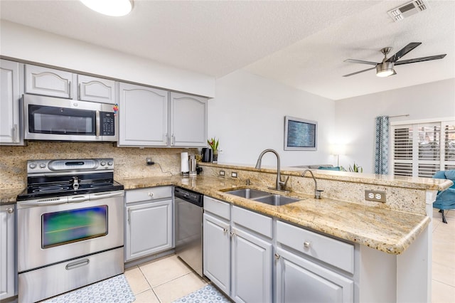 kitchen featuring visible vents, ceiling fan, appliances with stainless steel finishes, a peninsula, and a sink