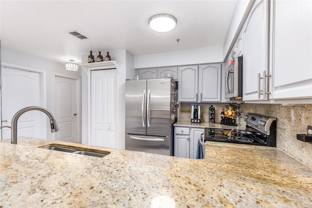 kitchen featuring a sink, gray cabinetry, visible vents, and stainless steel appliances