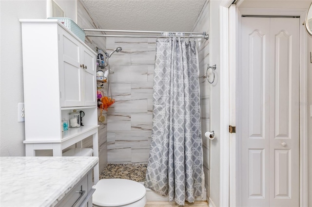 bathroom with a textured ceiling, a stall shower, vanity, and toilet