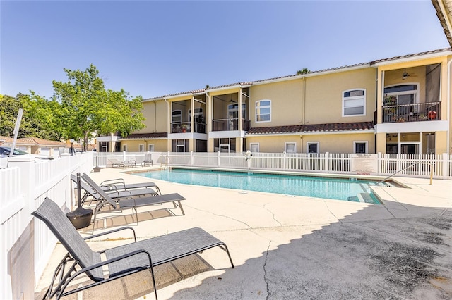 community pool with a patio and fence