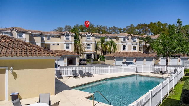 pool with a patio, fence, and a residential view