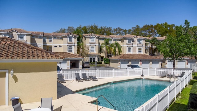 community pool with a residential view, a patio, and fence