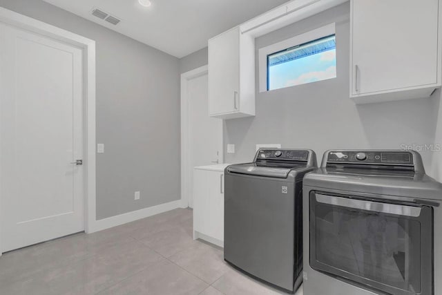 laundry room with baseboards, visible vents, light tile patterned flooring, cabinet space, and washer and clothes dryer