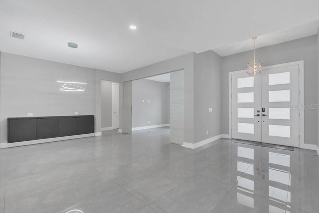 foyer entrance with baseboards, visible vents, tile patterned flooring, french doors, and a chandelier