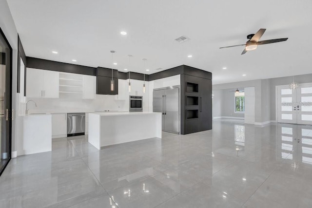 kitchen featuring visible vents, open shelves, ceiling fan, stainless steel appliances, and a center island