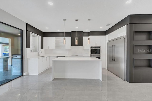 kitchen with a kitchen island, built in refrigerator, light countertops, range hood, and a sink