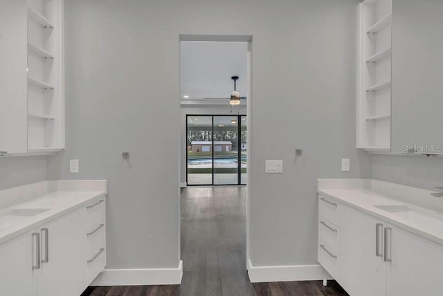 kitchen with open shelves, white cabinets, light countertops, and a sink