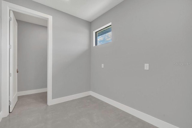 spare room featuring baseboards and concrete flooring