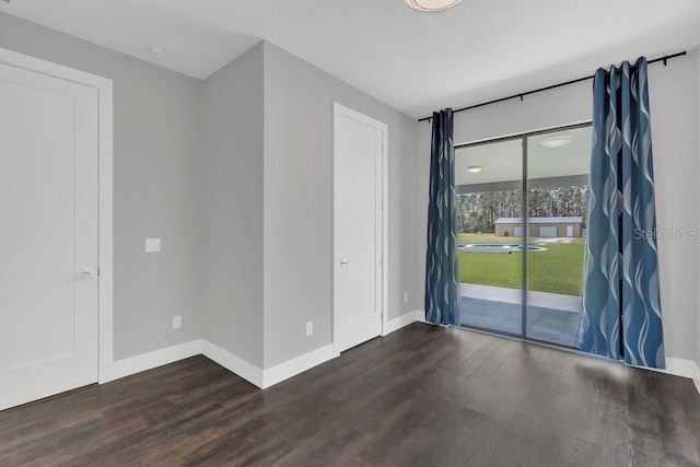 empty room featuring dark wood-style floors and baseboards