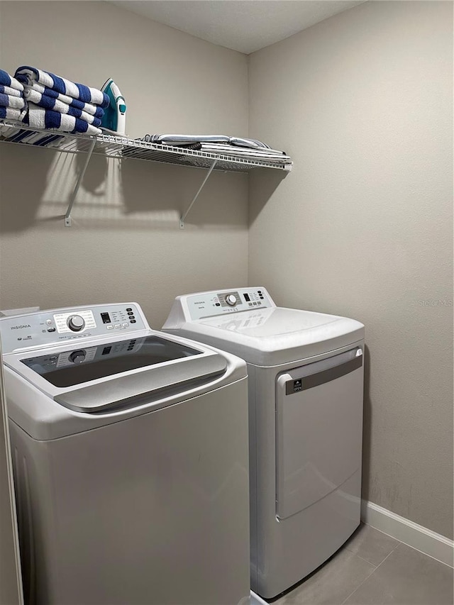 laundry room with baseboards, independent washer and dryer, light tile patterned flooring, and laundry area