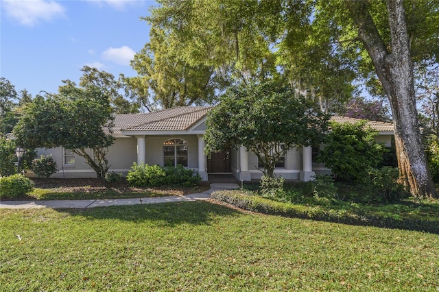 view of front of house featuring stucco siding, a tile roof, and a front lawn