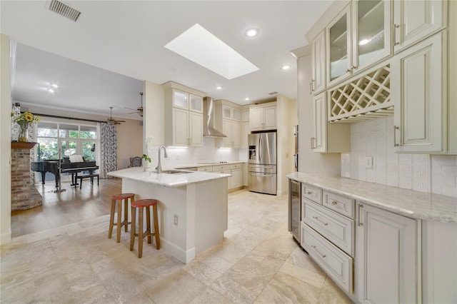 kitchen with visible vents, a peninsula, stainless steel fridge with ice dispenser, wine cooler, and wall chimney exhaust hood