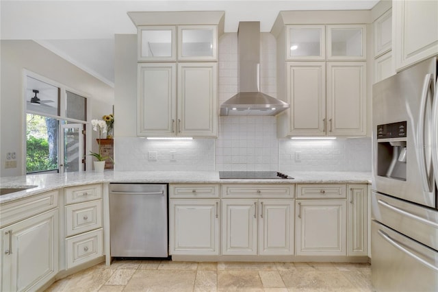 kitchen with decorative backsplash, appliances with stainless steel finishes, wall chimney exhaust hood, and light stone countertops