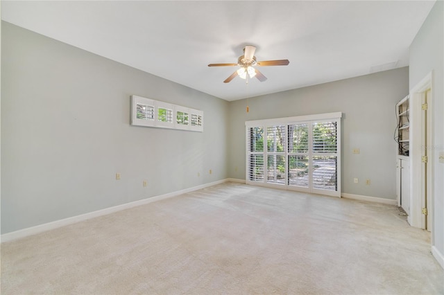 spare room with light colored carpet, baseboards, and ceiling fan