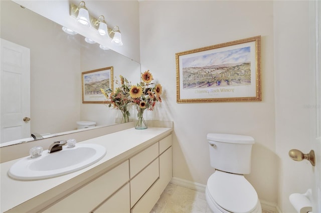 half bath featuring baseboards, toilet, and vanity