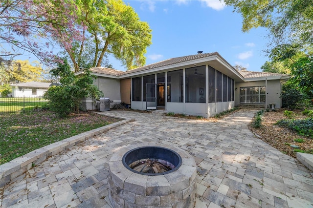 rear view of house with stucco siding, a patio, fence, a sunroom, and a tiled roof