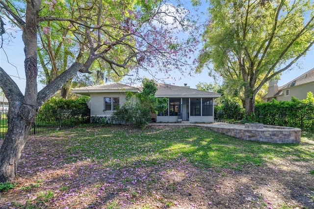 rear view of property with a lawn, fence, a sunroom, and stucco siding