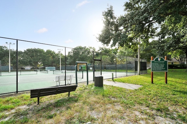 view of tennis court featuring a yard and fence