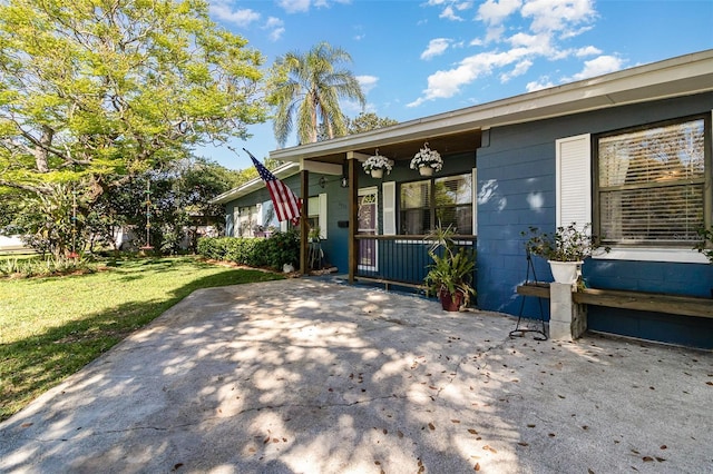 view of front of house with a porch, concrete block siding, and a front lawn