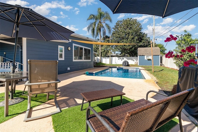 view of swimming pool featuring a fenced backyard, an outdoor structure, a storage shed, a patio area, and a lawn