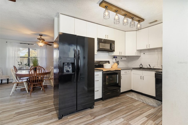 kitchen with a sink, ceiling fan, black appliances, white cabinets, and tasteful backsplash